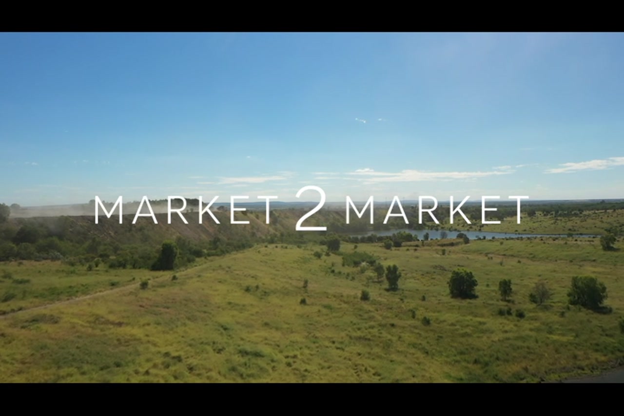 Aerial footage over green countryside and a lake / dam and a truck driving along a ridge