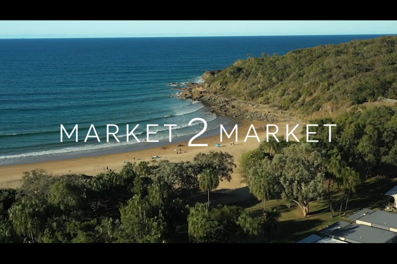 Aerial footage of surfers at beach with rocky headline