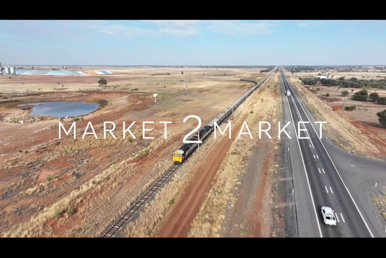Aerial footage of freight train traveling along track, next to a highway